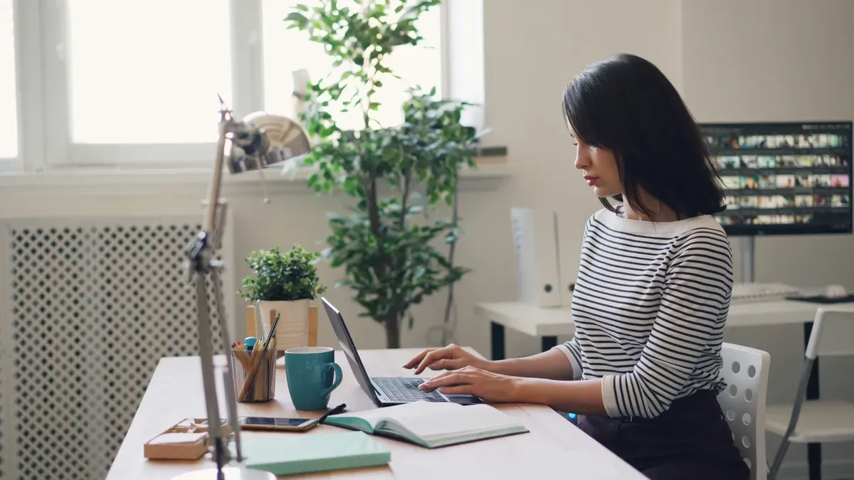 Collaboratrice travaillant sur ordinateur portable dans un bureau de PME